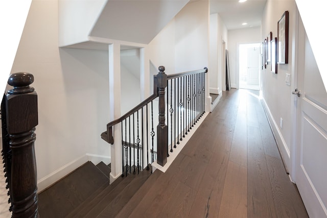 hallway featuring dark wood-type flooring, recessed lighting, an upstairs landing, and baseboards