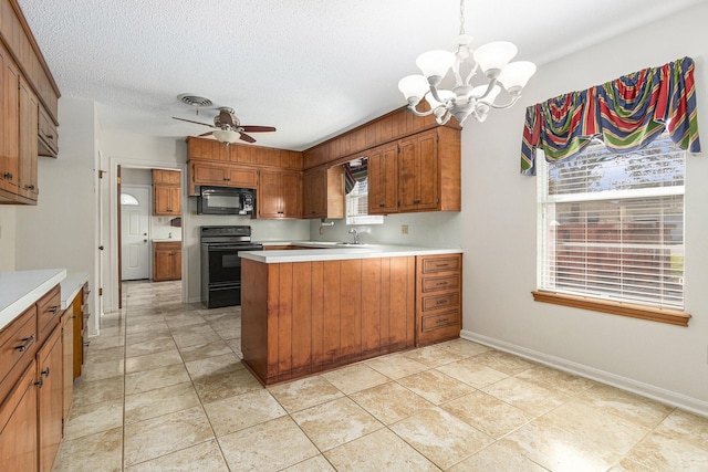 kitchen with ceiling fan with notable chandelier, light countertops, black appliances, brown cabinetry, and decorative light fixtures