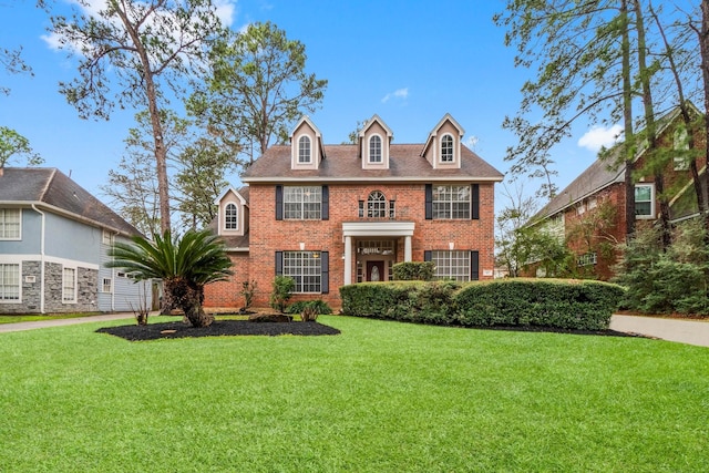 colonial home featuring a front yard and brick siding