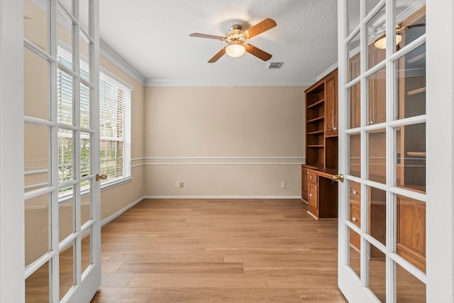 empty room featuring ornamental molding, french doors, light wood-style flooring, and baseboards