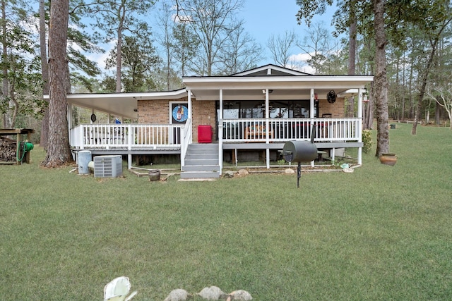 view of front facade with a deck, brick siding, a front lawn, and a porch