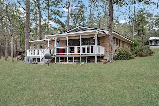 view of front facade featuring covered porch, brick siding, and a front yard