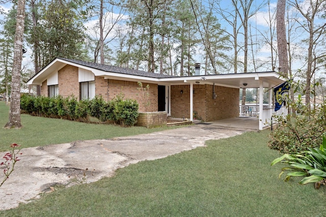 view of front of house with a front yard, brick siding, driveway, and an attached carport