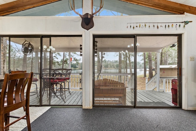 unfurnished sunroom with a healthy amount of sunlight, a water view, and vaulted ceiling with beams