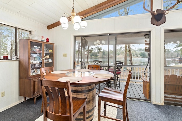 carpeted dining room featuring a water view, an inviting chandelier, and lofted ceiling with beams