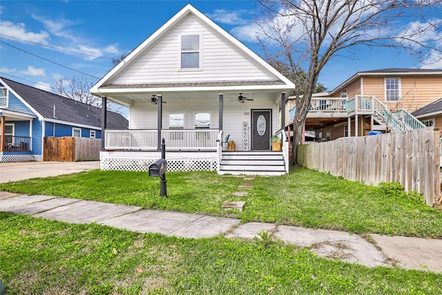 bungalow-style home with covered porch, a front yard, fence, and a ceiling fan