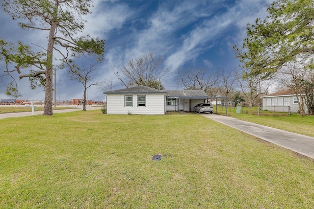 view of front of home featuring driveway, fence, a front lawn, and a carport