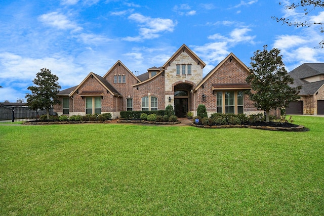 view of front facade with stone siding, brick siding, a front yard, and fence