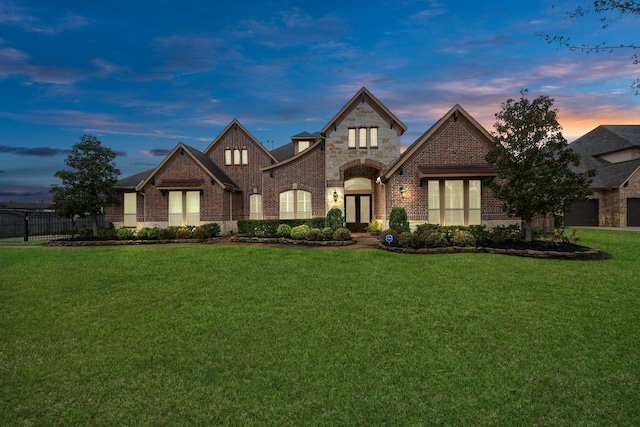 french country style house with brick siding, fence, and a front lawn