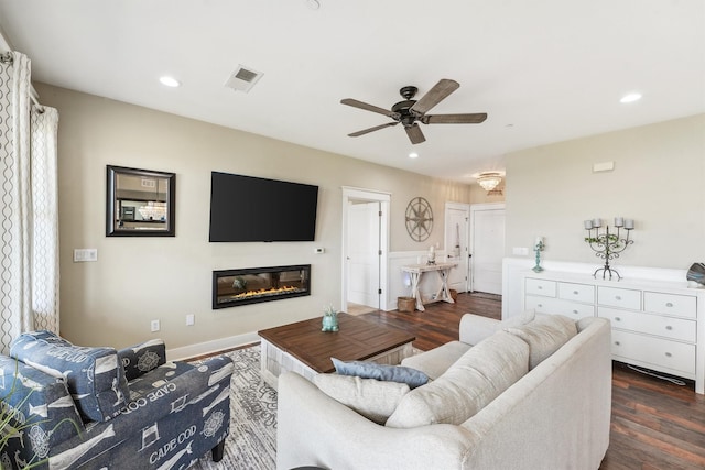 living area with visible vents, recessed lighting, a glass covered fireplace, and dark wood-style flooring