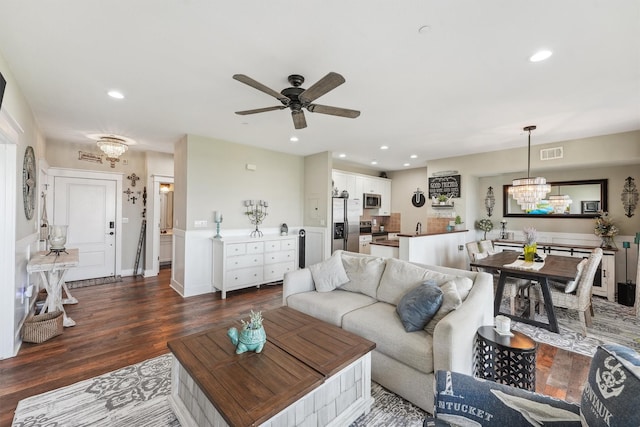 living room with visible vents, baseboards, recessed lighting, dark wood-type flooring, and ceiling fan with notable chandelier