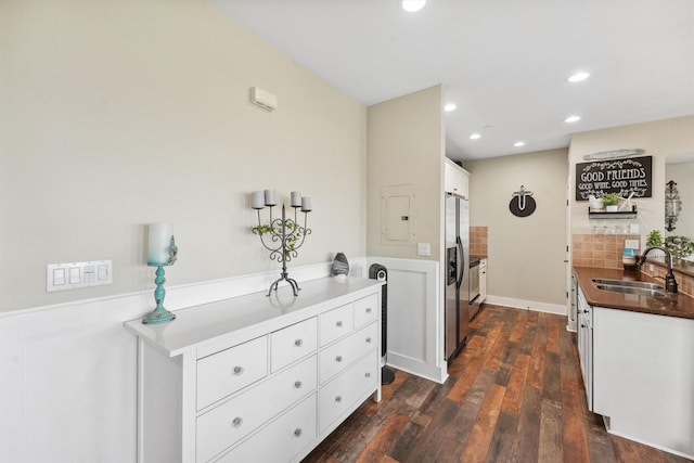 kitchen featuring recessed lighting, dark wood-style flooring, a sink, white cabinets, and stainless steel fridge