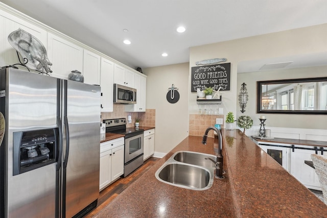 kitchen featuring backsplash, appliances with stainless steel finishes, white cabinetry, and a sink