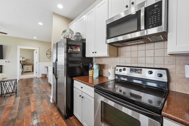 kitchen featuring dark countertops, decorative backsplash, appliances with stainless steel finishes, dark wood-style floors, and white cabinets