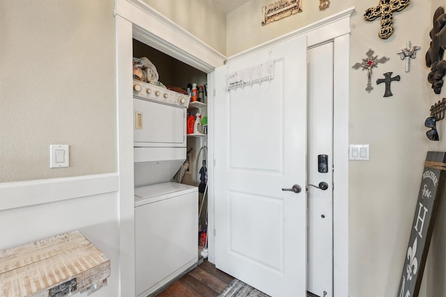 washroom featuring stacked washer and clothes dryer, dark wood-style flooring, and laundry area