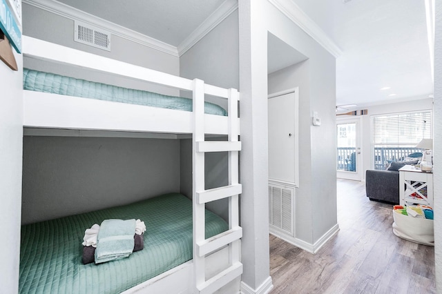 bedroom with baseboards, wood finished floors, visible vents, and crown molding