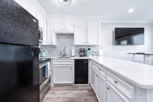 kitchen featuring tasteful backsplash, light countertops, a sink, a peninsula, and black appliances