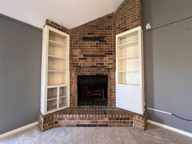 unfurnished living room featuring a textured ceiling, a fireplace, carpet flooring, built in features, and vaulted ceiling