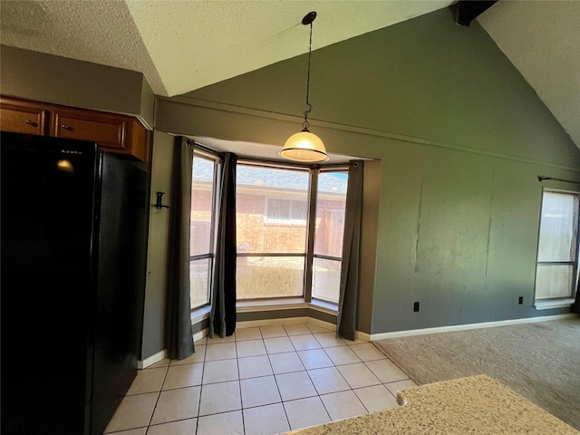 interior space featuring light tile patterned floors, brown cabinets, freestanding refrigerator, vaulted ceiling, and pendant lighting