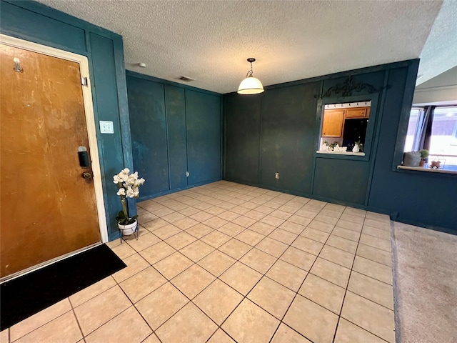 interior space featuring visible vents, a decorative wall, a textured ceiling, and light tile patterned floors