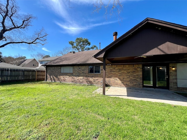 back of house featuring brick siding, a yard, fence, and a patio