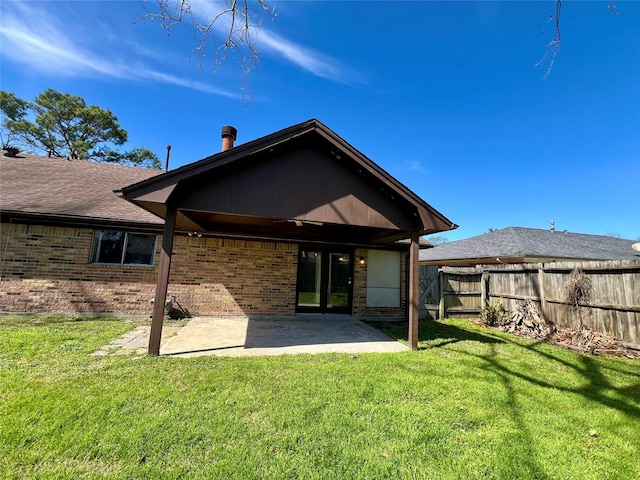 rear view of property featuring brick siding, a lawn, a patio area, and fence