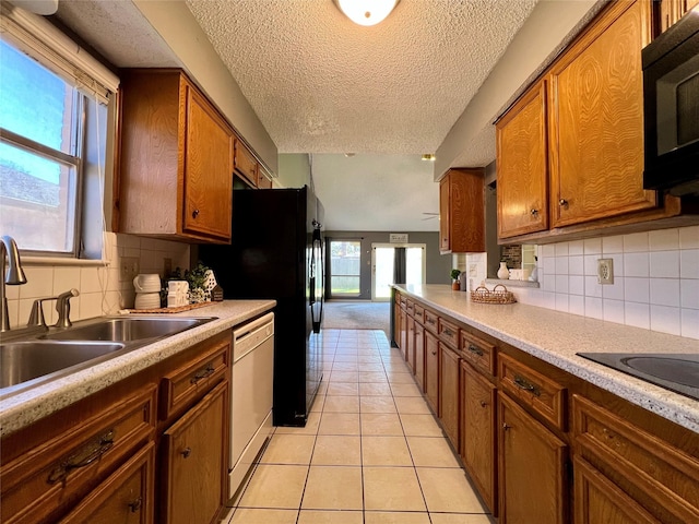 kitchen featuring brown cabinets, light countertops, light tile patterned flooring, a sink, and black appliances