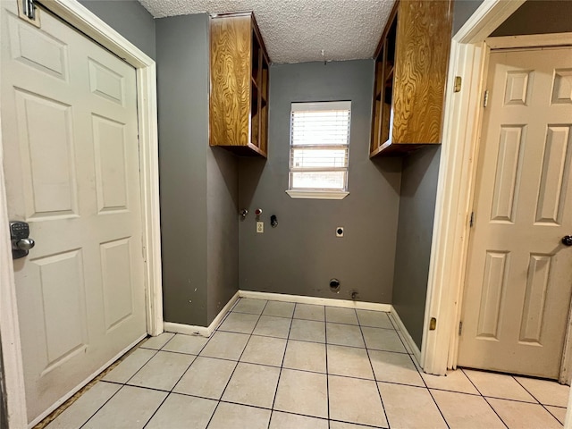 laundry area featuring cabinet space, light tile patterned floors, baseboards, hookup for a gas dryer, and a textured ceiling