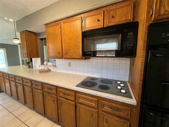 kitchen with brown cabinetry, light countertops, backsplash, and black appliances