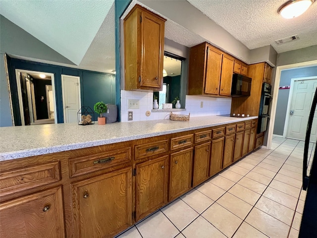 kitchen with black appliances, light tile patterned floors, visible vents, and brown cabinetry