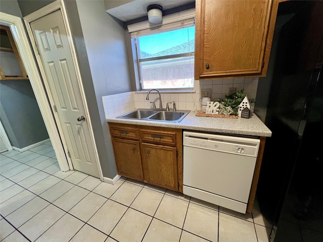 kitchen with light tile patterned floors, tasteful backsplash, brown cabinets, white dishwasher, and a sink