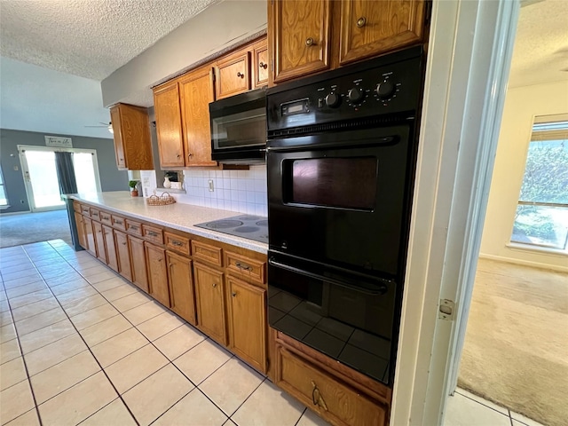 kitchen featuring brown cabinets, light colored carpet, light countertops, a textured ceiling, and black appliances