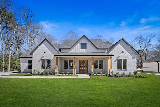 view of front of home featuring brick siding, a shingled roof, french doors, board and batten siding, and a front yard