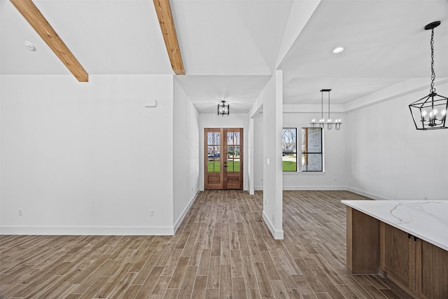 entryway featuring french doors, light wood-style flooring, beam ceiling, and baseboards