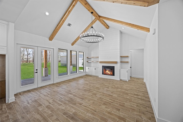 unfurnished living room featuring a fireplace, visible vents, a notable chandelier, and wood finished floors