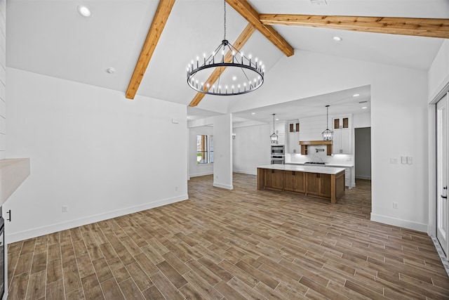 unfurnished living room featuring dark wood-type flooring, beamed ceiling, and a notable chandelier