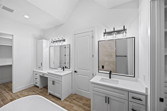 bathroom with wood tiled floor, vaulted ceiling, two vanities, and a sink