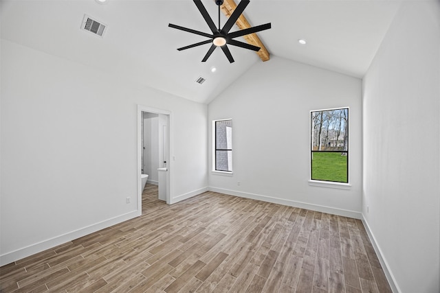 spare room with light wood-type flooring, a wealth of natural light, beam ceiling, and visible vents