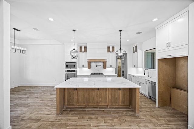 kitchen with a large island, white cabinetry, stainless steel appliances, and light stone counters