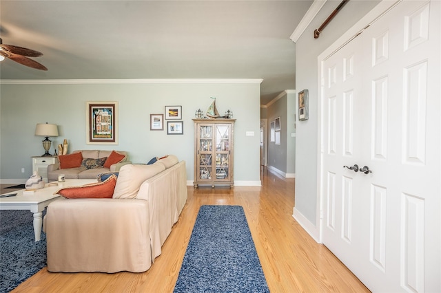 living room with ornamental molding, light wood finished floors, a ceiling fan, and baseboards