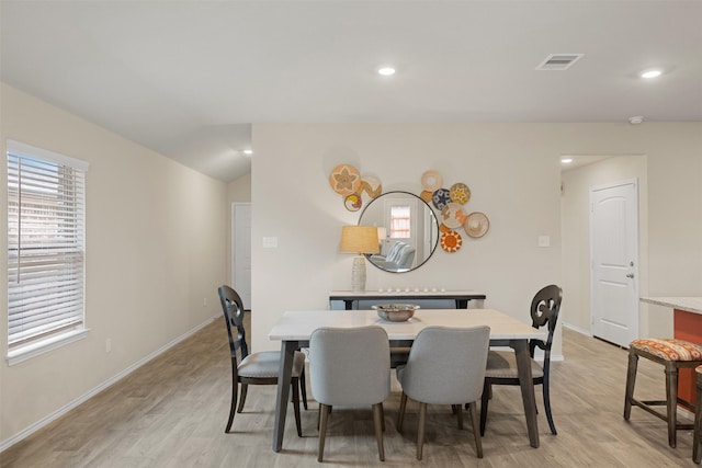 dining space with lofted ceiling, light wood-style flooring, and baseboards