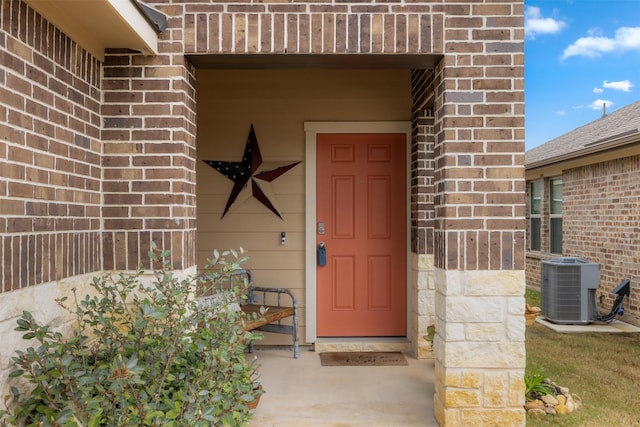 entrance to property with central AC unit and brick siding