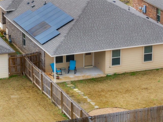 rear view of property with a shingled roof, a patio area, and a fenced backyard