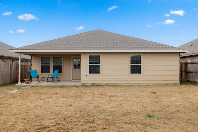 rear view of property with a fenced backyard, a patio, and roof with shingles