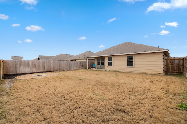 rear view of property with a yard, a fenced backyard, a shingled roof, and a patio