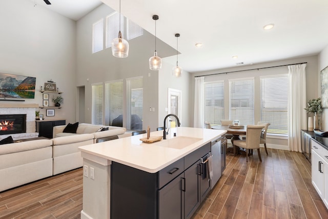 kitchen with pendant lighting, a center island with sink, light countertops, open floor plan, and a sink