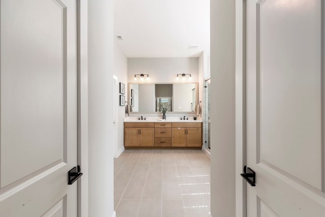 bathroom featuring tile patterned floors, a sink, a shower stall, and double vanity