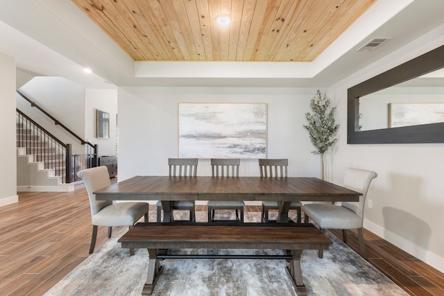 dining room with wooden ceiling, stairway, a tray ceiling, and wood finished floors