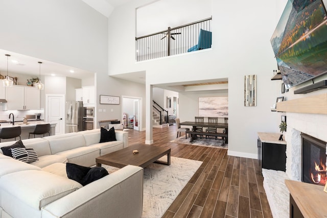 living room with stairs, wood finish floors, a fireplace, and baseboards