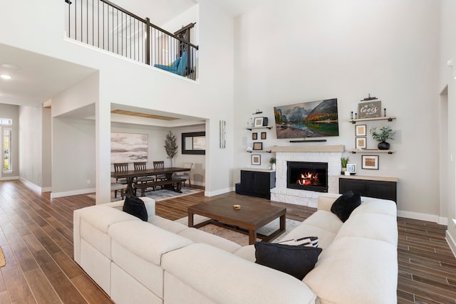 living area with a warm lit fireplace, wood finish floors, and baseboards